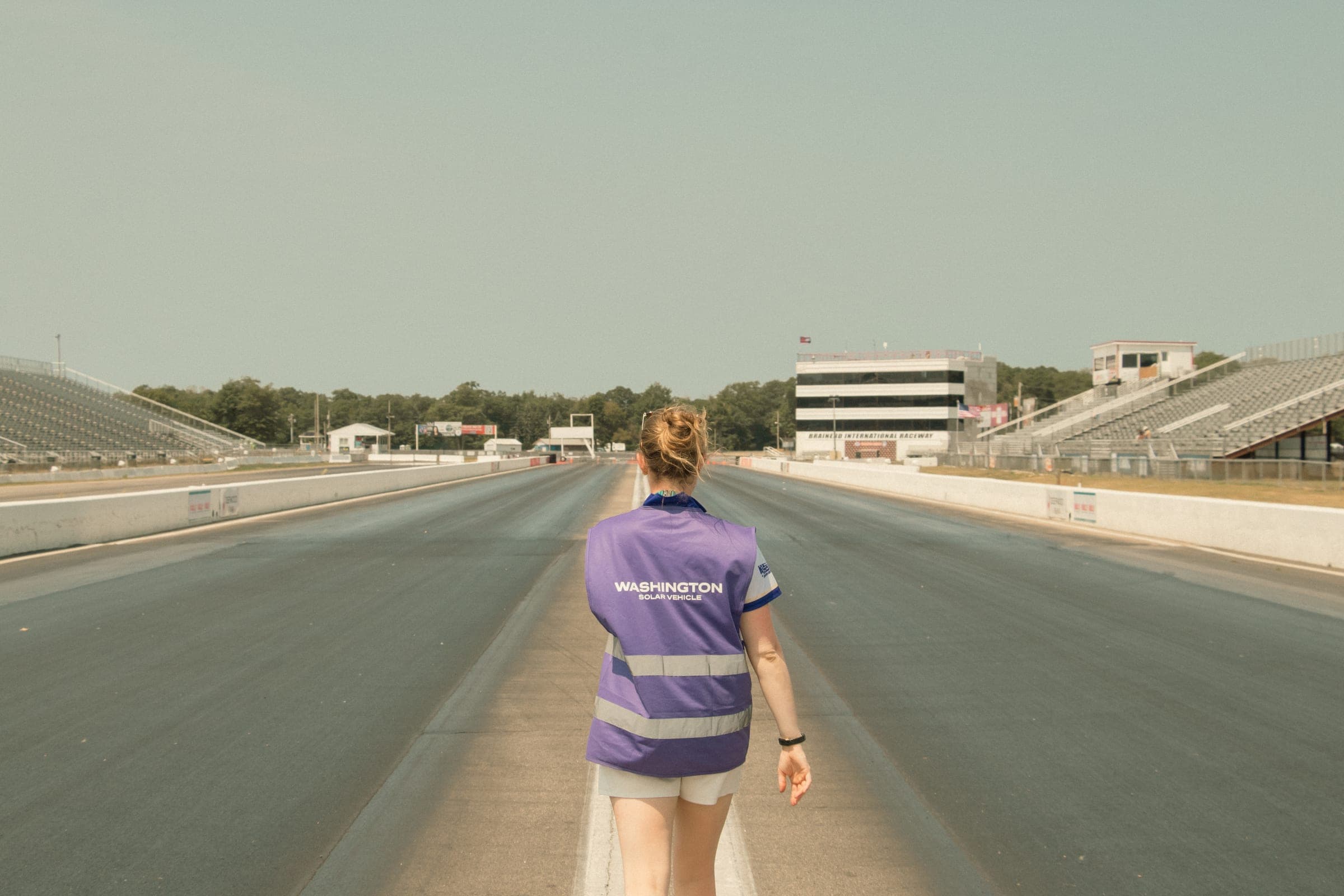 A team member in a team vest walking down an empty drag strip