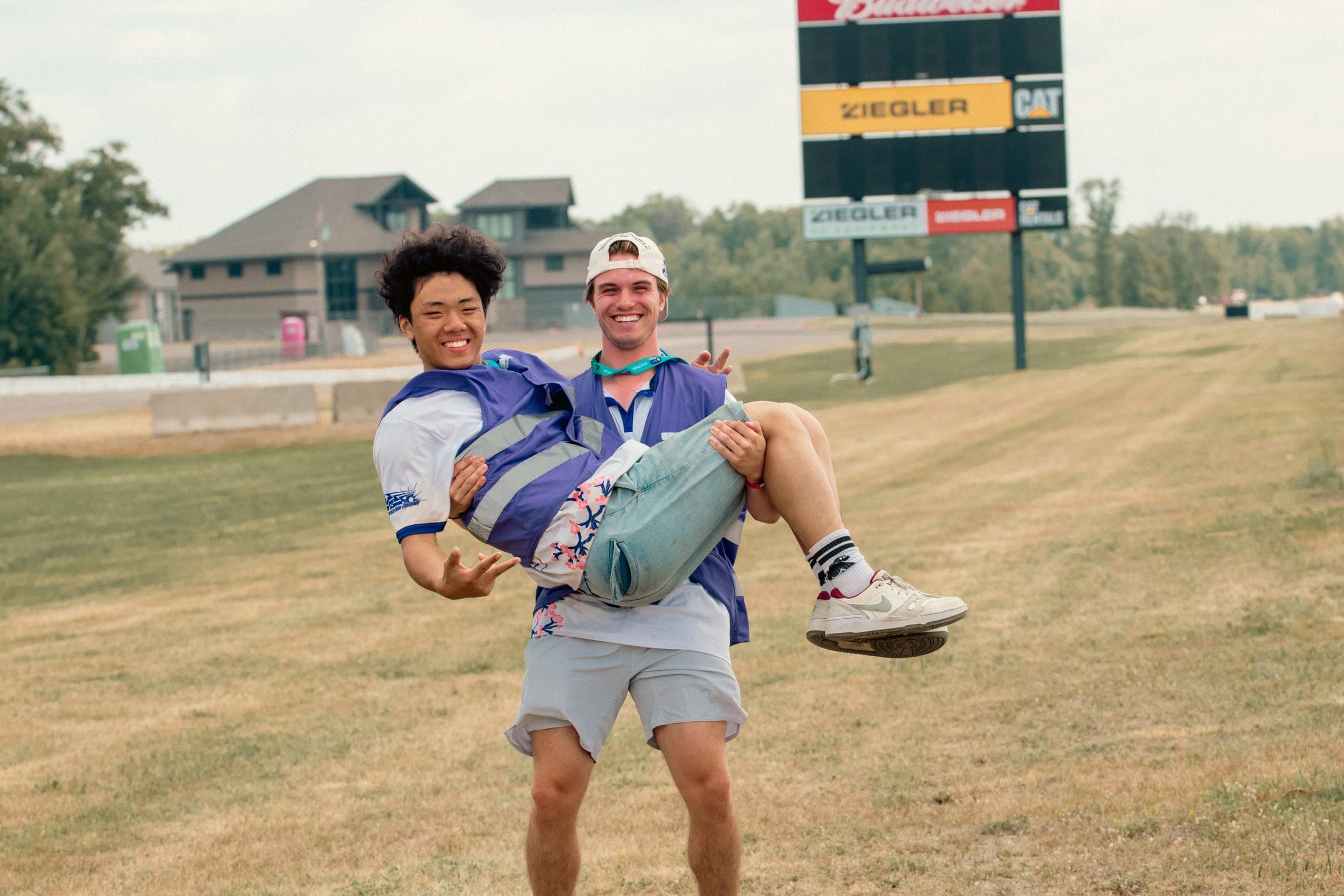 Two team members laughing at the track, one lifting the other