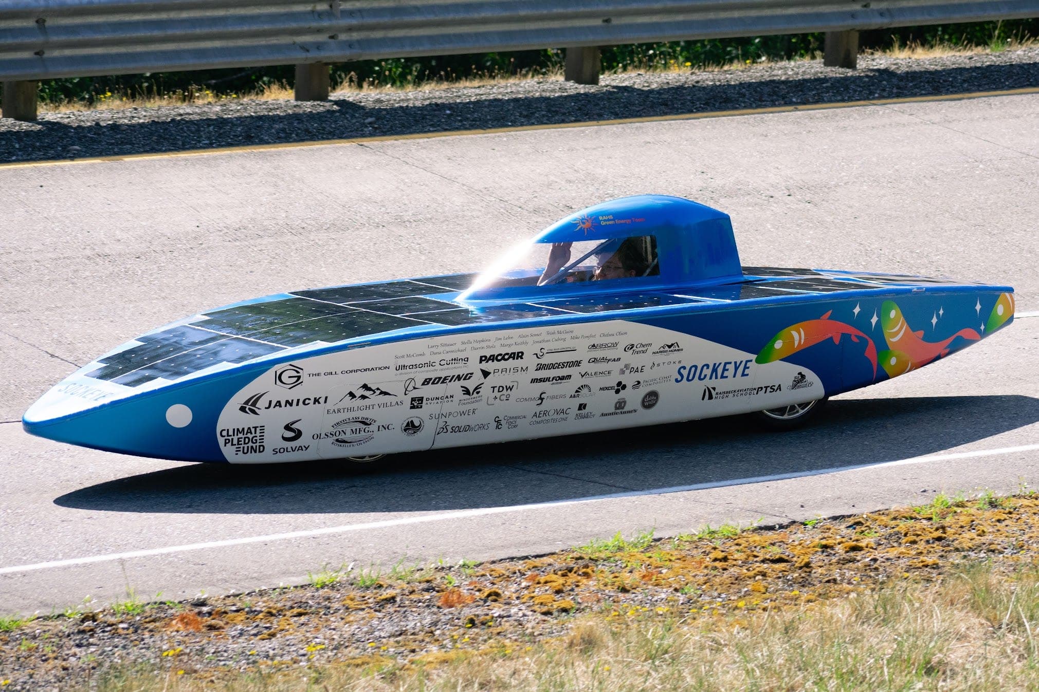 Sockeye, the team's 2025 solar car, running on track in full side profile with its salmon livery